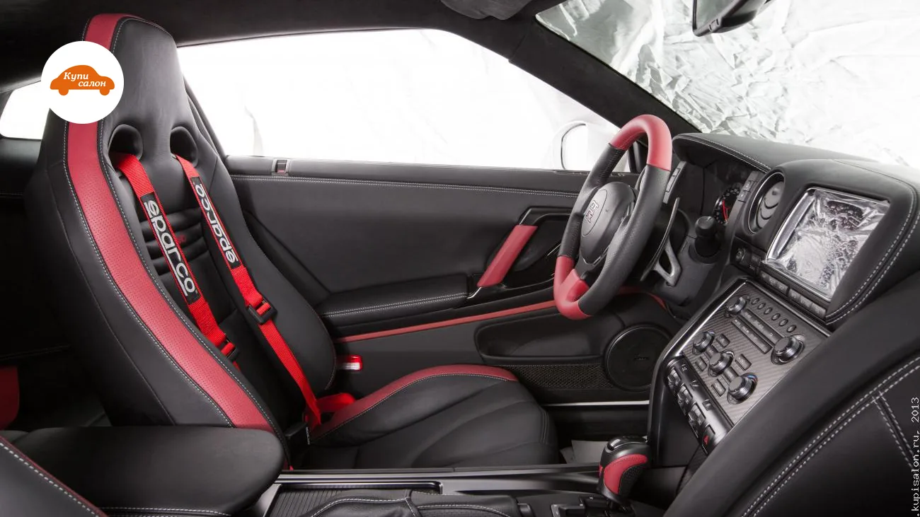 Перетяжка салона Nissan Gt-r черной кожей с красными вставками, белой строчкой и карбоновыми элементами.